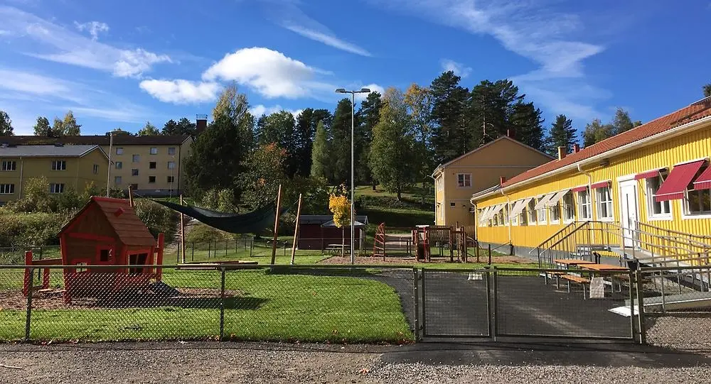 Förskolan Villekulla ett gult enplans hus med gråa och röda markiser och ett grönt staket kring lekparken utanför.