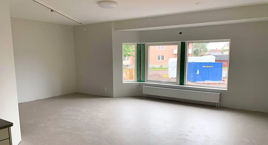 Tomt lägenhetsrum med vita väggar och ljusgrått golv Fridensborg.