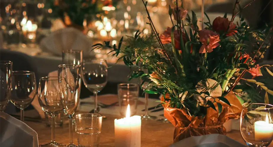Fint dukat bord med glas, blomsterarrangemang och tända blockljus