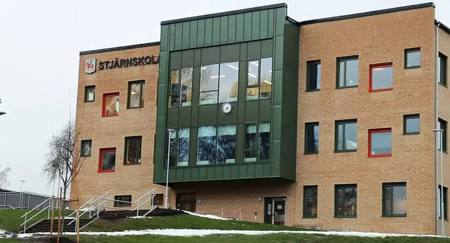 Framsidan av Stjärnskolan, en ljusbrun tegelbyggnad med gröna partier i mitten.
