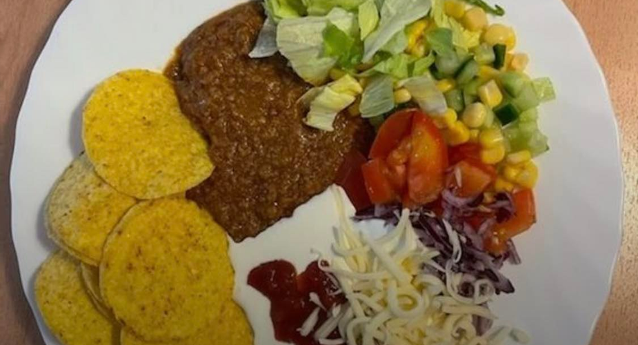 Tacochips, köttfärs, riven ost och grönsaker på en tallrik