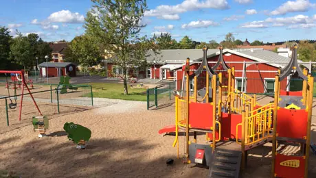 Lekplats med ställningar i rött och gult framför förskolan Lyckan