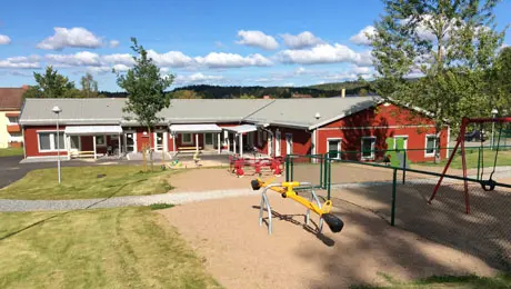 Lekplats med ställningar i rött och gult framför förskolan Lyckan