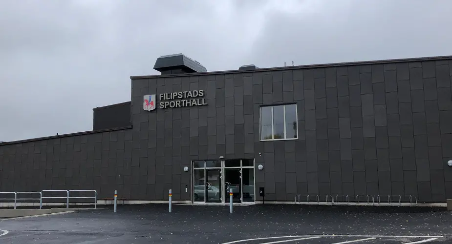 Filipstads sporthall, grå byggnad med platt tak och kommunens logotyp på väggen