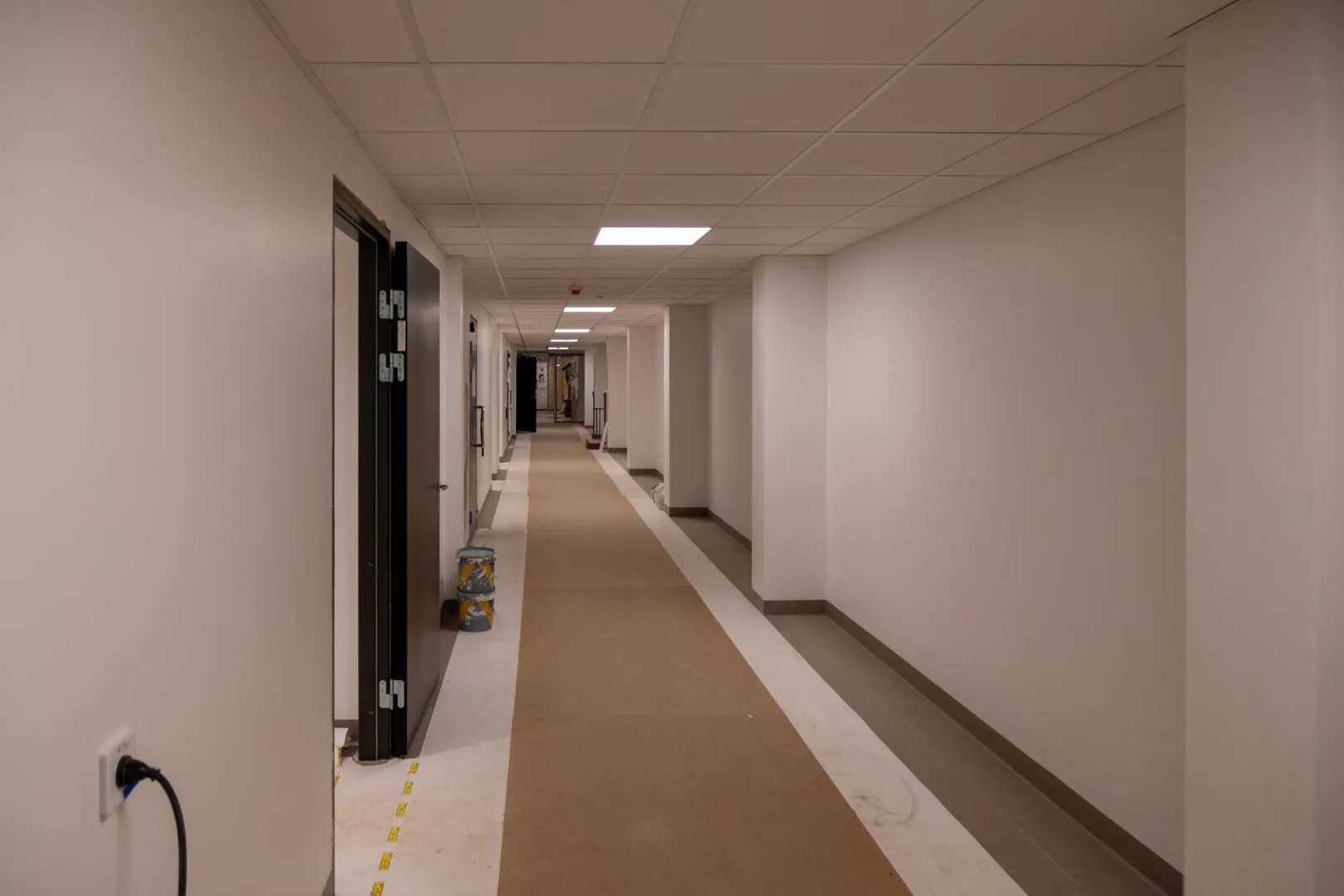 Vit korridor med golv skyddad av kartonger.