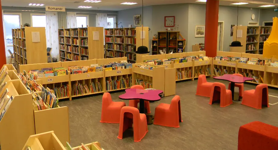 Bibliotekshuset i Filipstad fullt med böcker och två bord och fyra stolar vid varje