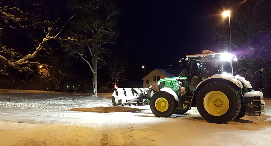 Traktor som plogar snö i mörkret