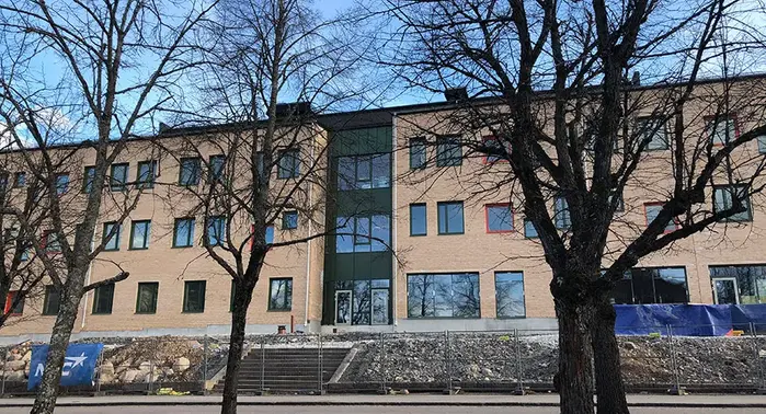 Brun byggnad med glasfönster bakom träd